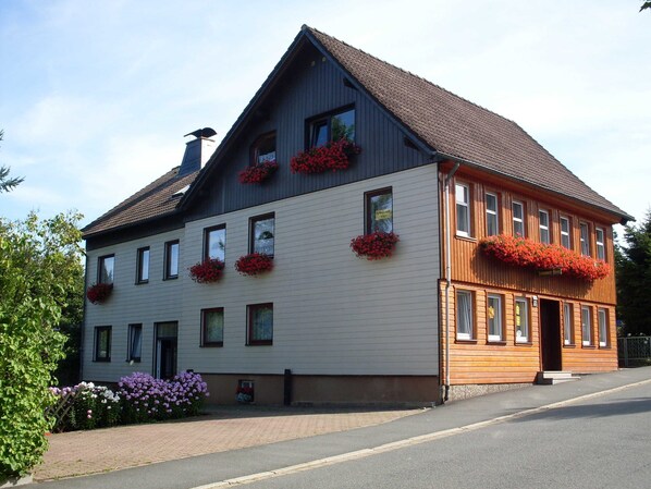 A two-story building with multiple windows, some with flower boxes.