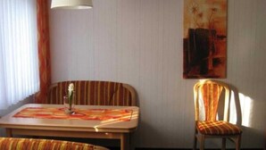 Una habitación con un sofá a rayas, una mesa de comedor con un mantel individual, una silla, una lámpara y un cuadro en la pared.