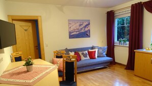 Ein Wohnzimmer mit einem Holzesstisch, einem blauen Sofa und einem Bild an der Wand.