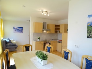 A compact kitchen with a dining table, chairs, and a small plant centerpiece. - Apartment for 11 persons - Alpenjuwel (Laimach)