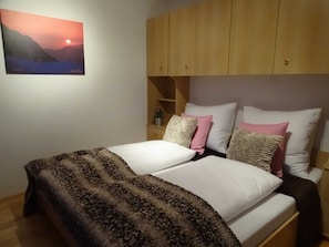 A bedroom with a bed, pillows, a nightstand, and a wall-mounted picture. - Apartment for 11 persons - Alpenjuwel (Laimach)