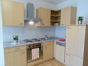 A kitchen with light wooden cabinets, a stainless steel stove, a built-in oven, a sink, and a dishwasher.