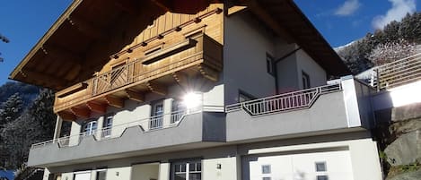 En toetagers bygning med en træbalkon, en bænk og en garageport.