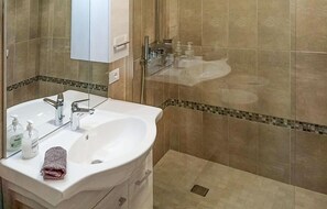 Bathroom features a sink, mirror, and mosaic-tiled walls.