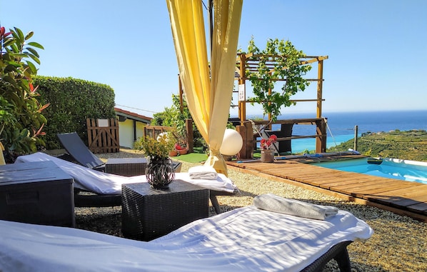 Relax by the ocean with a serene pool area, lounge chairs, and a shaded pergola.