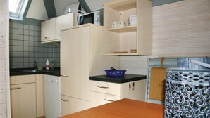 Una cucina compatta con un forno a microonde, un lavandino e una ciotola blu sul piano di lavoro.