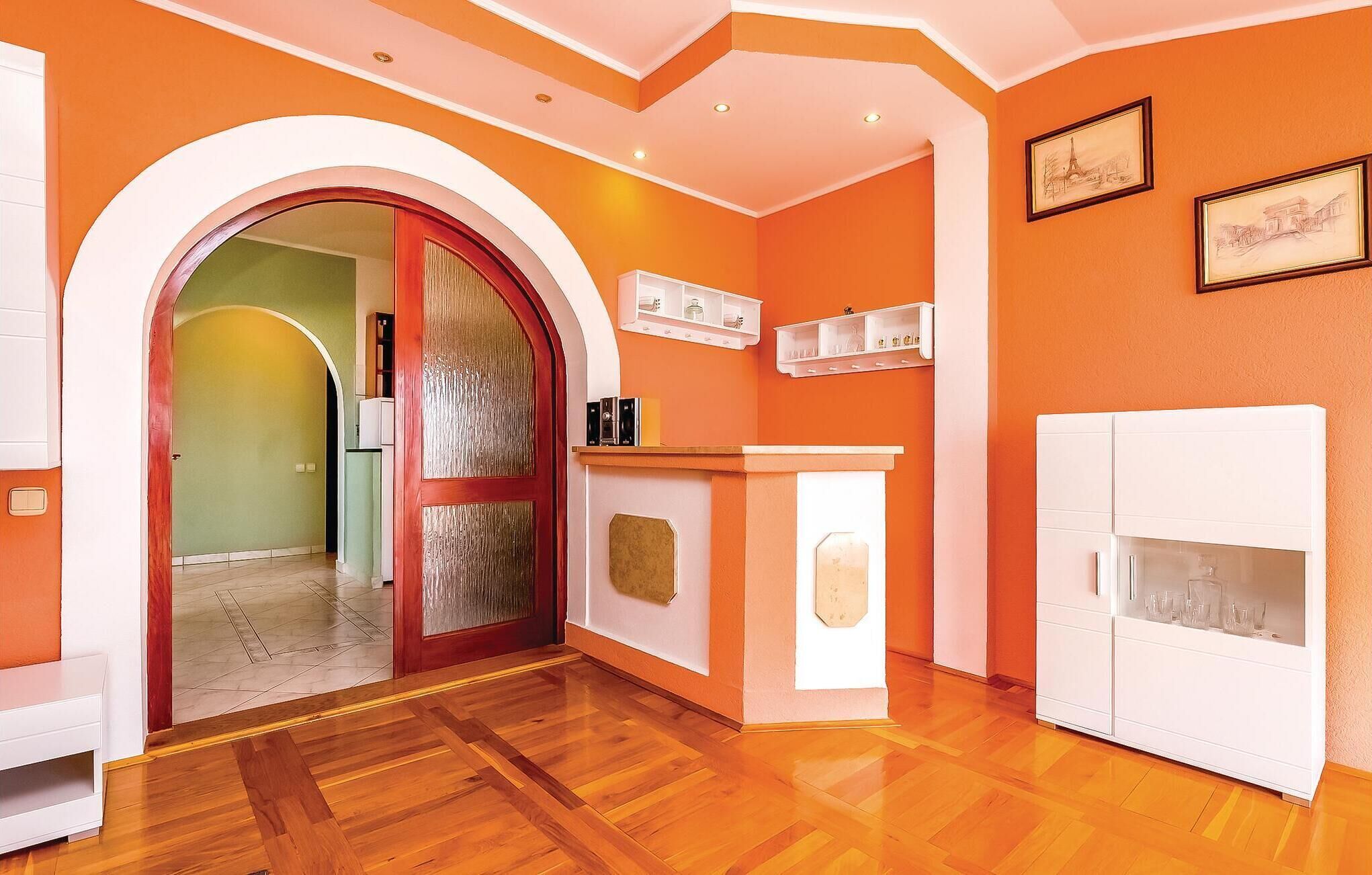 A room with a wooden floor, a red-framed door, white cabinets, and a fireplace.