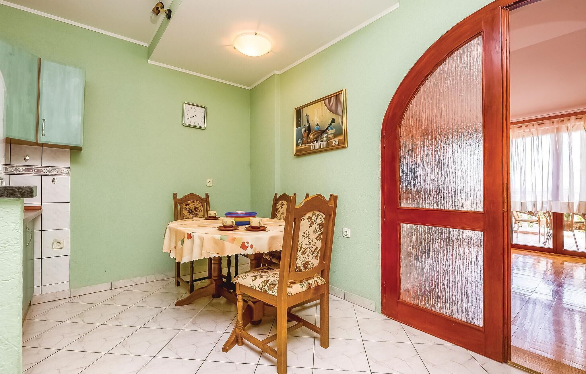 Un comedor con una mesa dispuesta para dos personas, un reloj en la pared y un cuadro sobre la mesa.