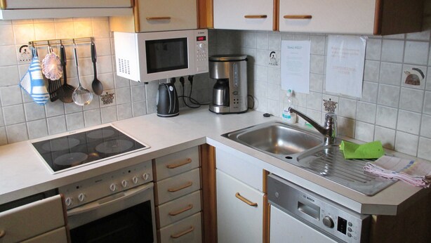 A compact kitchen with a microwave, coffee maker, and dishwasher. - Apartment 1 - Ferienhof Nussbaumer (Gaisberg)