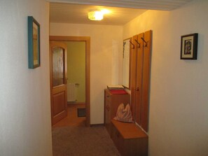 Un couloir avec un radiateur, un banc et un miroir.