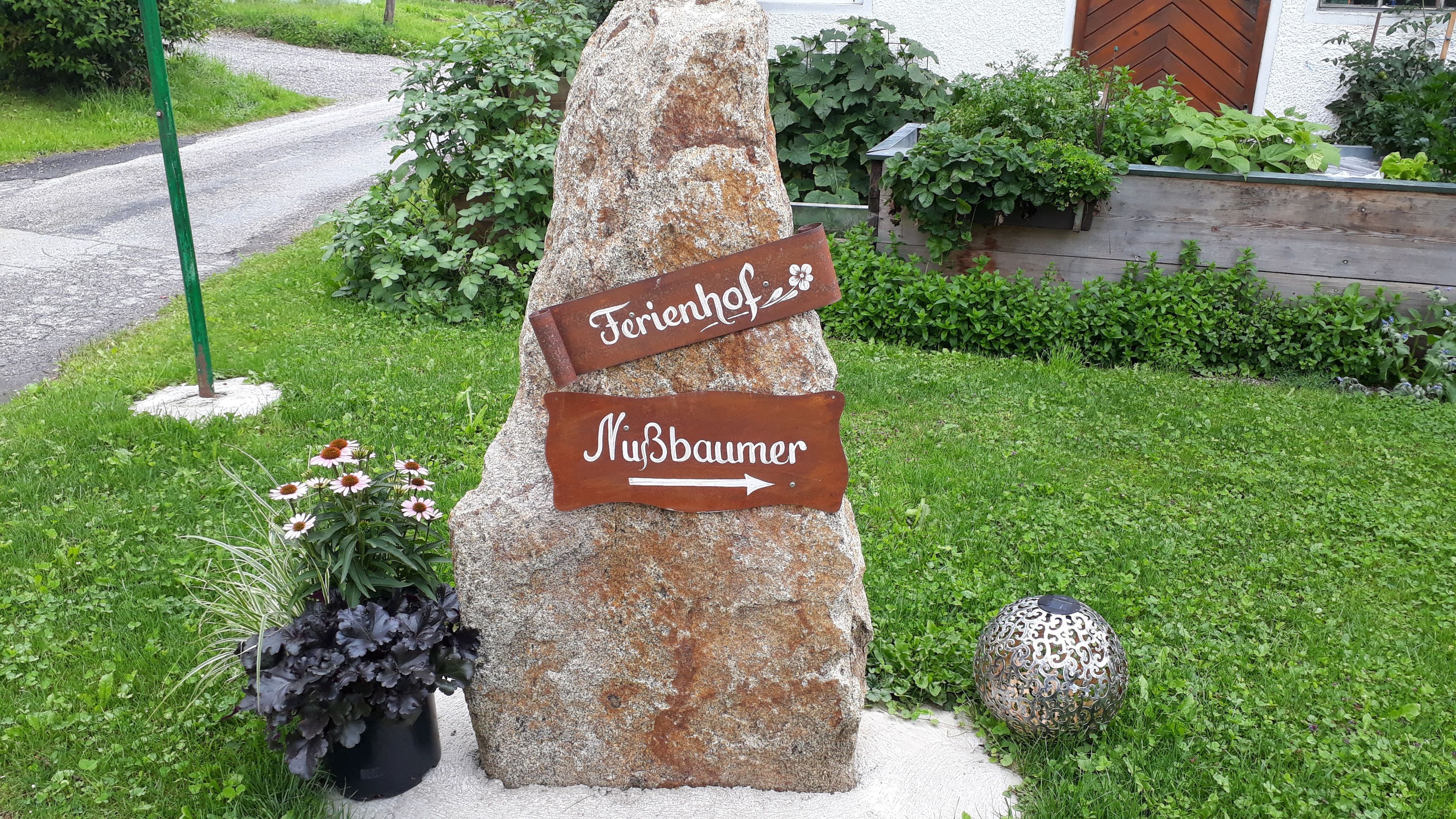 Um sinal de pedra com setas indicativas e texto que mostra os caminhos para 'Feriendorf' e 'Nybbaumer'.