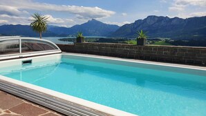 A swimming pool with a mountain view, a palm tree, and a potted plant. - Apartment 1 - Ferienhof Nussbaumer (Gaisberg)