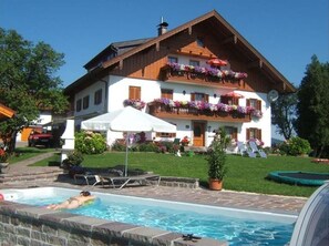 Un bâtiment à deux étages doté d’une piscine, d’un patio couvert et d’une pelouse bien entretenue.