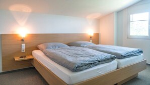 Una camera da letto moderna con una testiera in legno, due comodini e una finestra che lascia entrare luce naturale.