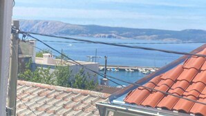 A view from a window overlooking a coastal area with a tiled roof and a clear sky. - Holiday home with internet access and sea view (Novi Vinodolski)