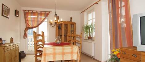 A dining area with a wooden table, chairs, a chandelier, and a cabinet.