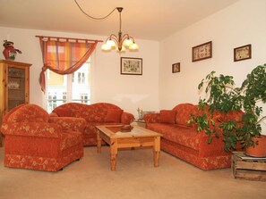Ein Wohnzimmer mit zwei Sofas, einem Holztisch, einer Chandelier und einer Topfpflanze.