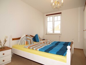 Ein Schlafzimmer mit Bett, Nachttischen, einem Fenster und einer Pendelleuchte.