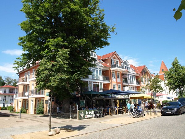 A row of traditional European-style buildings with balconies, a pub, and outdoor seating.