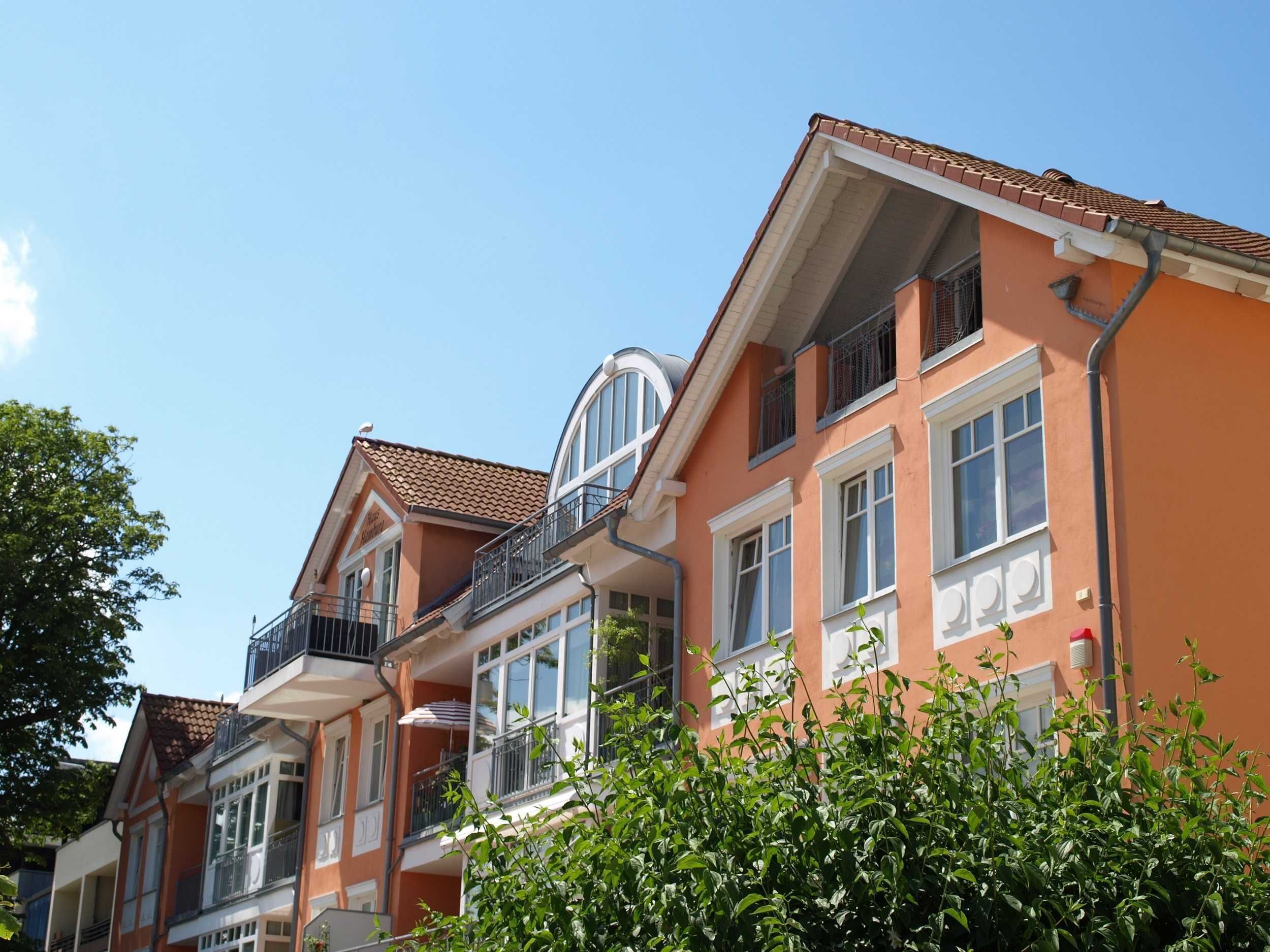 A row of terraced houses with balconies, large windows, and a clear sky.