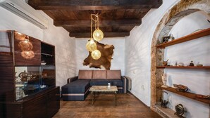 Un intérieur rustique avec un plafond en bois, un canapé en cuir, une vitrine et un mur en pierre agrémenté d’étagères.