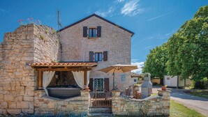 Une maison en pierre dotée d’un grand espace extérieur aménagé pour se détendre, d’un jacuzzi et d’une cheminée en pierre.