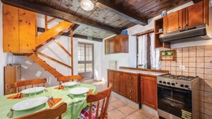 Une cuisine avec des meubles de rangement en bois, une cuisinière et un coin repas avec une table dressée pour quatre personnes.