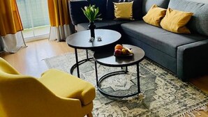 Una sala moderna con un sofá gris, cojines amarillos, una mesa de centro redonda y un sillón amarillo.
