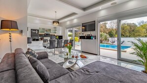 A modern living room with a sofa, a glass coffee table, and a view of a swimming pool. - Lovely home in Pula with sauna (Pula)