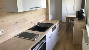 Eine moderne Küche mit weißen Schränken, einer Holzarbeitsplatte, einem eingebauten Backofen und einem Essbereich mit Tisch und Stühlen.