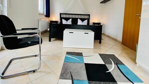 Een slaapkamer met een bed, nachtkastje, stoel en uitzicht.