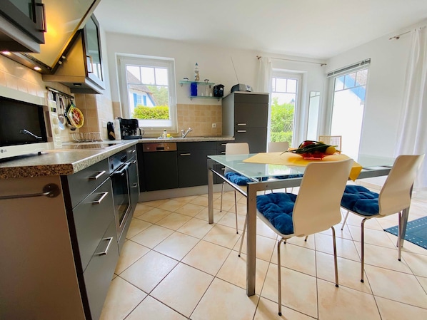A modern kitchen with a dining area, featuring a built-in oven, microwave, and a dining table with chairs.