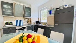 Een moderne keuken met een eettafel, een magnetron, een fornuis en kastjes.