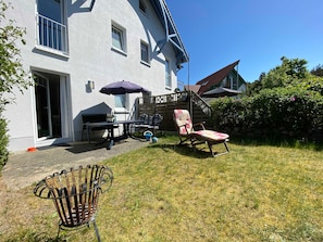 A house with a patio area, a barbecue setup, outdoor furniture, and a garden.