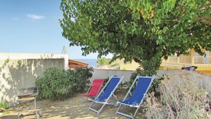 Un patio con una parrilla, tres sillones de descanso y vistas al mar.