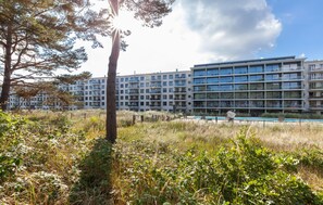 Un moderno edificio de apartamentos con piscina, rodeado de vegetación.