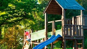 Une structure de jeux en bois comprenant un toboggan et une zone d’escalade.