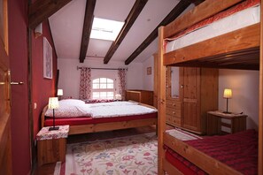 A bedroom with a bunk bed, a wooden wardrobe, a bedside table with a lamp, and a floral-patterned rug. - Apartment 1 - the horse - Holiday on Duckwitz Castle (Behren-Lübchin)