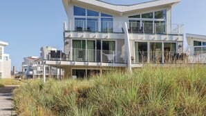 A modern two-story beachfront house with multiple balconies and large windows.