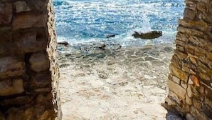Un sendero de piedra que conduce a una playa con olas rompiendo en la orilla.