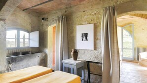 A rustic room with exposed brick walls, a wooden table, a small white cabinet, a window with a view, and a framed picture on the wall. - Beautiful home in Poggibonsi SI (Poggibonsi SI)