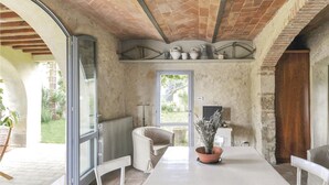 A dining area with a white table, chairs, and a potted plant. There is a window with a view of the garden, and a door leading outside. - Beautiful home in Poggibonsi SI (Poggibonsi SI)