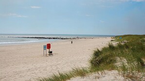 A beach with a signpost, a rocky breakwater, and a grassy dune. - Stunning home in Blåvand with sauna (Blåvand)