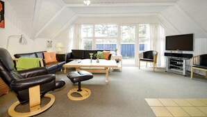 A spacious living room with a high ceiling, a large window, a flat-screen TV, and a wooden coffee table. - Stunning home in Blåvand with sauna (Blåvand)
