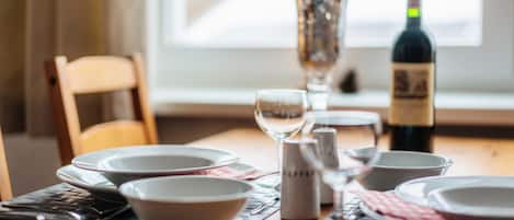 A dining table set with plates, bowls, cutlery, and a wine bottle.