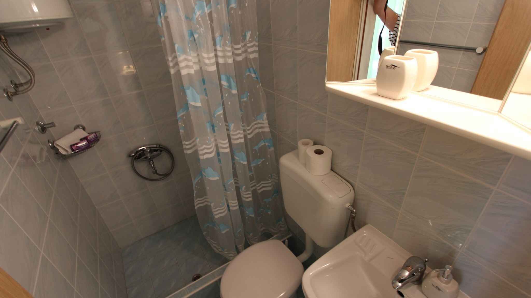 Une salle de bain équipée d’une douche, de toilettes, d’un lavabo et d’un miroir, ainsi que de produits de toilette.