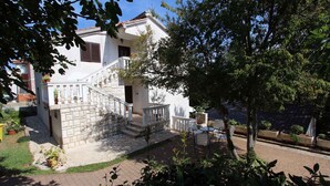 A two-story house with a stone staircase, a balcony, and a garden area with potted plants. - Studio with air conditioning and terrace (Porat)