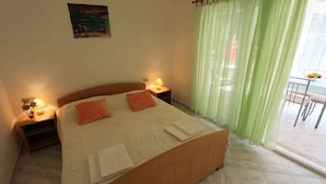 A neatly made bed with two pillows, a bedside table with a lamp, and a painting on the wall. - Studio with air conditioning and terrace (Porat)