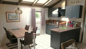 Una cucina compatta con zona pranzo, caratterizzata da un tavolo in legno, sedie, un'isola con lavello ed elettrodomestici moderni.