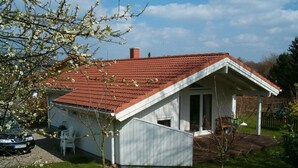 Una piccola casa con tetto in tegole rosse, facciata bianca e un portico coperto.